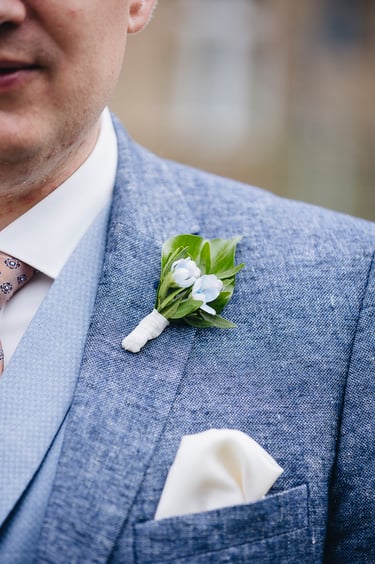 Close-up of the grooms lapel with pinned flowers.