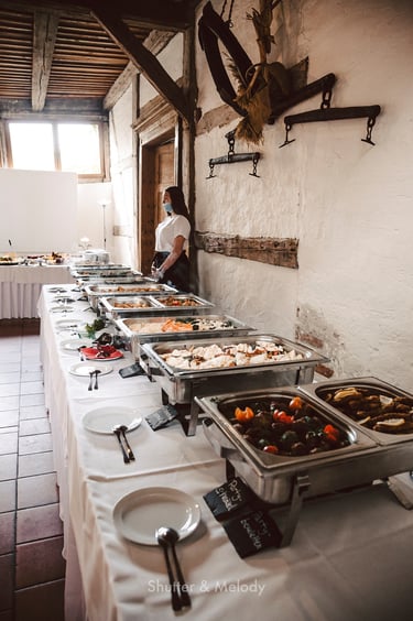 A waitress standing next to a buffet at a wedding reception.