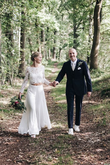 Bride and groom walking down a path holding hands.