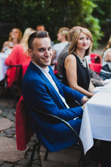 Hochzeitsgäste sitzen an Tischen.