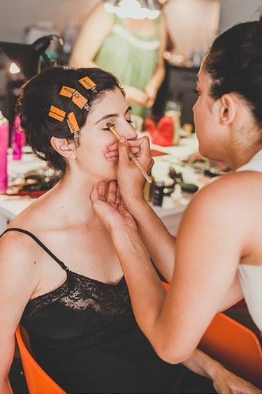Bride in a slip getting ready, having her make-up done.
