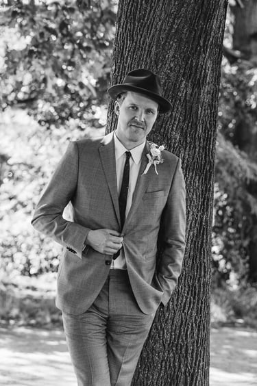 Groom with a hat opening a button on his suit.