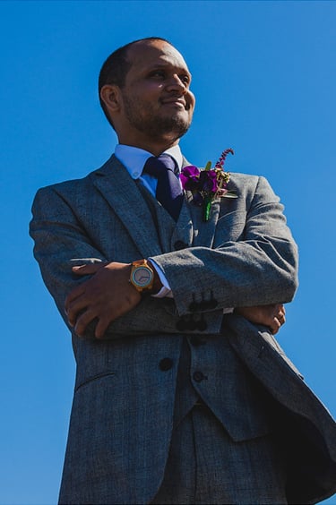 Groom looking on with the blue sky as a background.