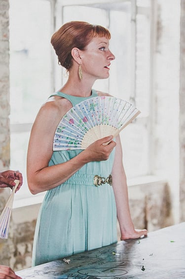A bridesmaid in a light blue dress using a fan.
