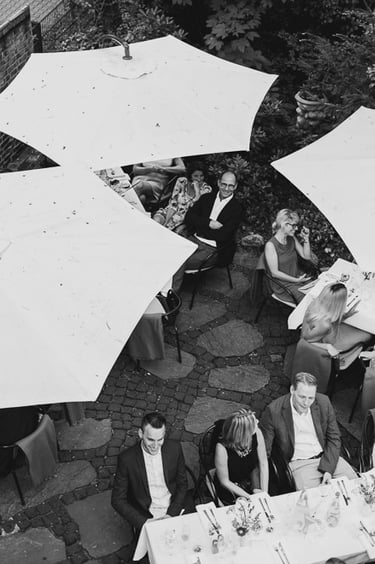 Wedding guests sitting at tables under umbrellas.