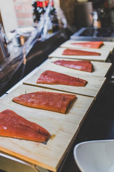 Lachsfilets, die auf Holzbretter genagelt sind.