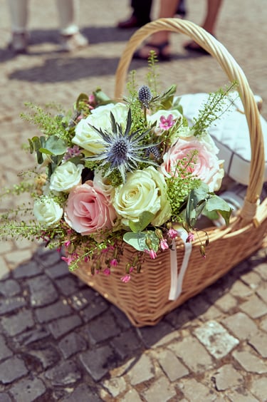 Blumen in einem Korb auf Pflastersteinen.