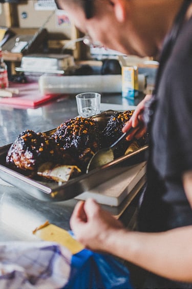 Ein Koch schmort in der Küche Fleischkeulen.