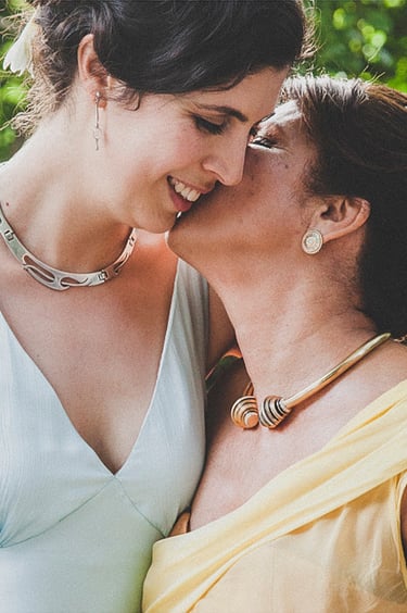 Die Mutter der Braut küsst die Braut auf die Wange.