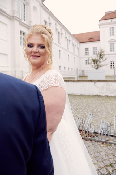 Bride looking over the shoulder of the groom into the camera.