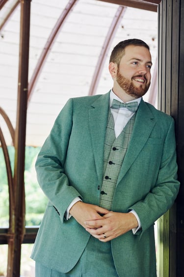 Groom in a green suit looking into a distance.