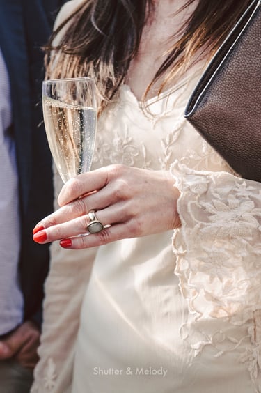 A close-up of a wedding guest's hand holding a glass of sparkling wine.