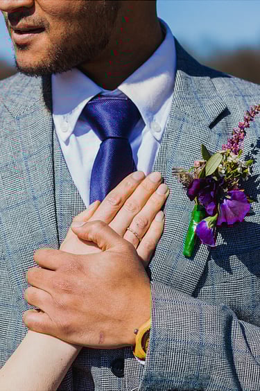 Groom holding brides hand on his chest. 