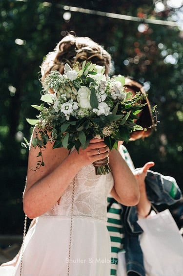 Bride holding up her flowers in the sunshine.