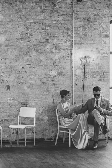 A couple sitting on chairs next to a brick wall.