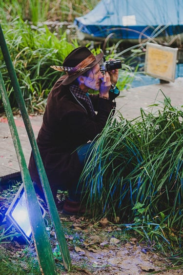Man wearing a fedora hat taking photographs.