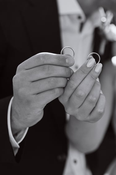 Wedding rings being held by bride and groom.