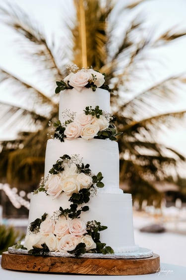 a wedding cake with white flowers on a wooden board