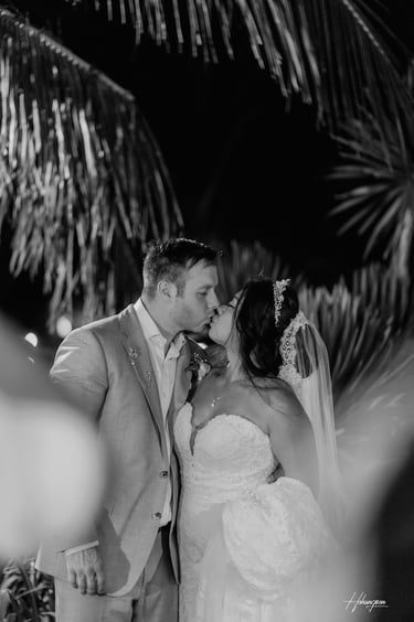 a bride and groom kissing in a tropical setting