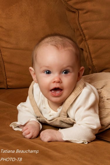 Photo d'un adorable bébé aux yeux bleus, allongé sur le ventre et souriant