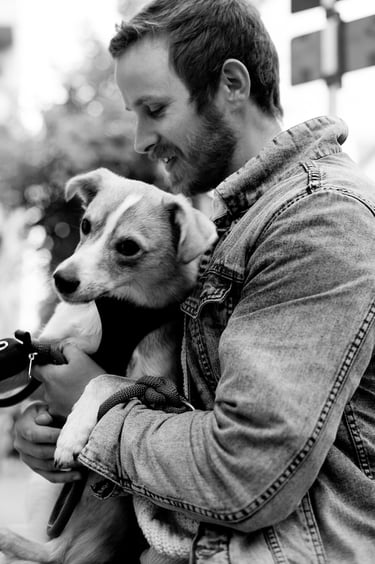 A young man with his dog wearing a jean jacket.