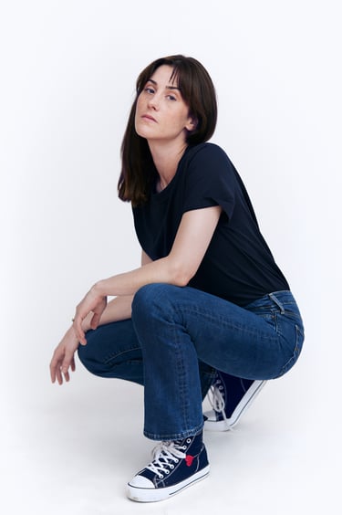 A young woman crouching in a photography studio.
