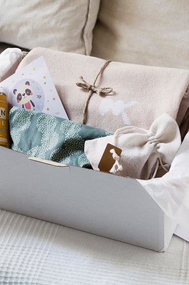 Eine Box mit einem Kissen, Öl, einem Lätzchen, einer Decke und Wandtaschen.
