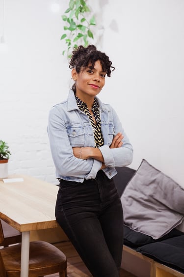 Ein Porträt von Emilia Roig in einem Café, die eine Jeansjacke trägt.