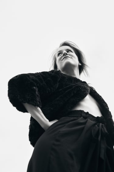 A portrait of a woman in a fake fur coat and black pants.