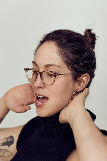 Ein Kopfbild einer singenden Frau mit Brille.