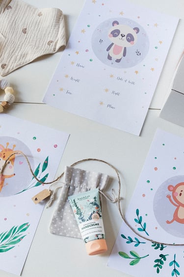 A flat lay with a toy, hand cream, colourful paper and a bib.