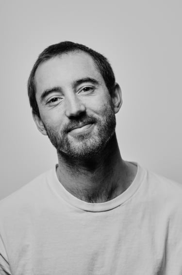 Headshot of a smiling man in black and white.