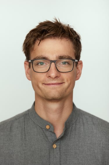 A headshot of a young man wearing glasses.