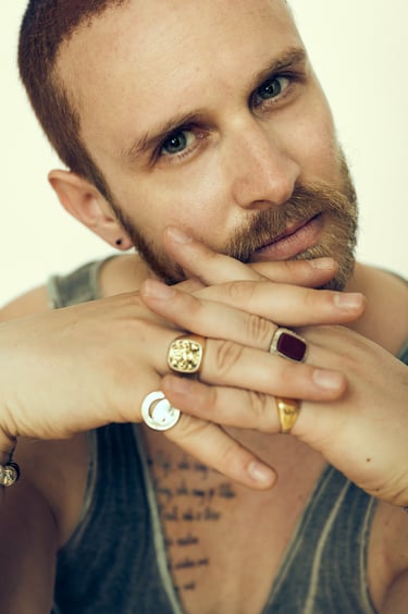 Headshot of an actor wearing rings looking into camera.
