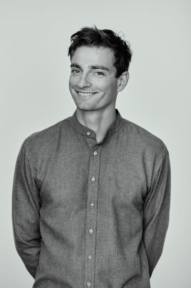 Ein Mann, der in einem Fotostudio lächelt und dessen Hände auf dem Rücken gefesselt sind.