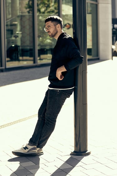 Man photographed leaning on a lamp post.