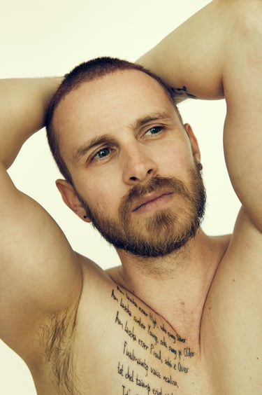 A shirtless man with a tattoo looking to the side.
