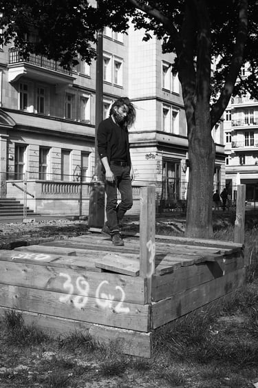 A black and white portrait of a man walking on wooden boards.