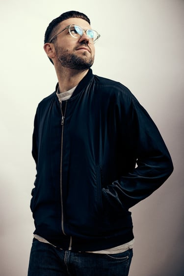 Mann, fotografiert in einem Studio mit Spiegelung in der Brille.