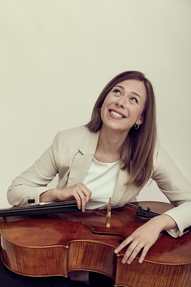 Frau schaut lächelnd nach oben und hält ein Cello.