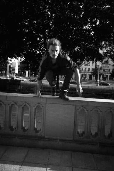 A man in a sports jacket jumping over a wall.