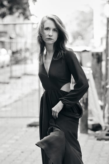 A young woman wearing a dress standing in the street.