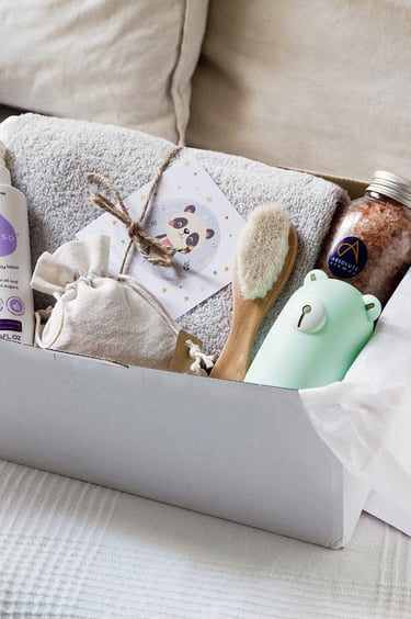 Box with a lotion, brush, towel, salt and a toy.