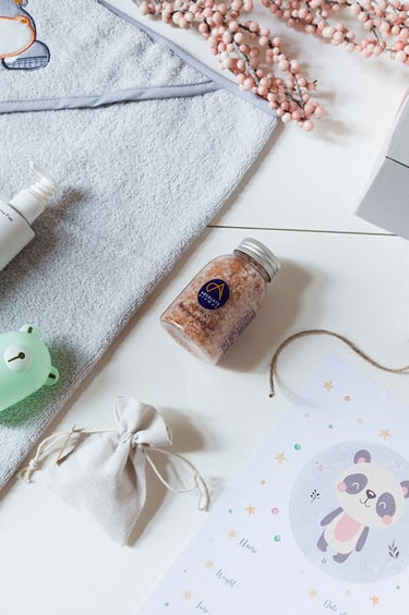Ein Flatlay mit einer Lotion, einer Bürste, einem Handtuch, Salz und einem Nagelset.