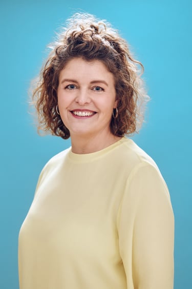 Portrait of a smiling woman in a yellow blouse.