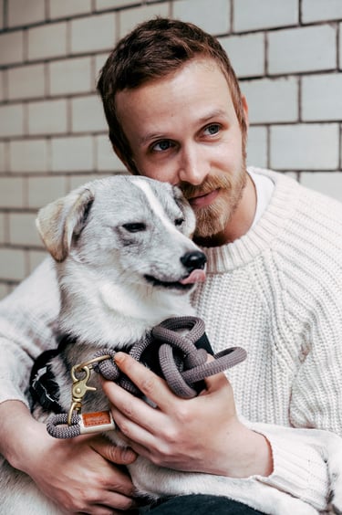 A portrait of a young man hugging his dog sticking out its tongue.