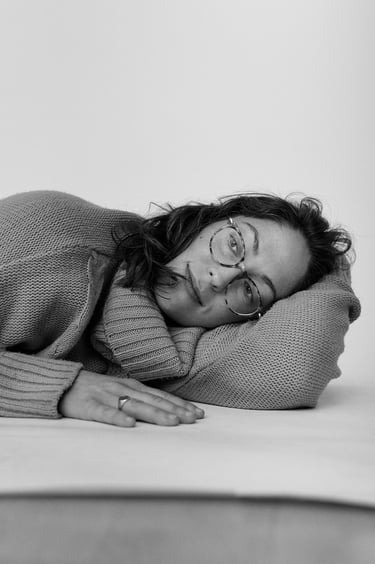 Eine junge Frau, die einen Pullover trägt und auf dem Boden eines Studios liegt.