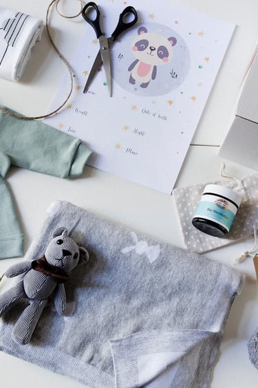 Ein Flatlay mit einem Teddy, einem Schlafanzug, einer Tasche, einer Decke und einem Handtuch.