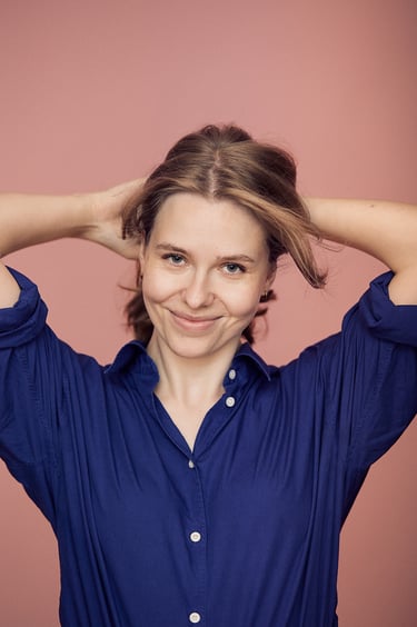 A woman wearing a blue shirt fixing her hair.