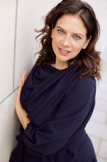 A woman next to a wall looking into the camera.